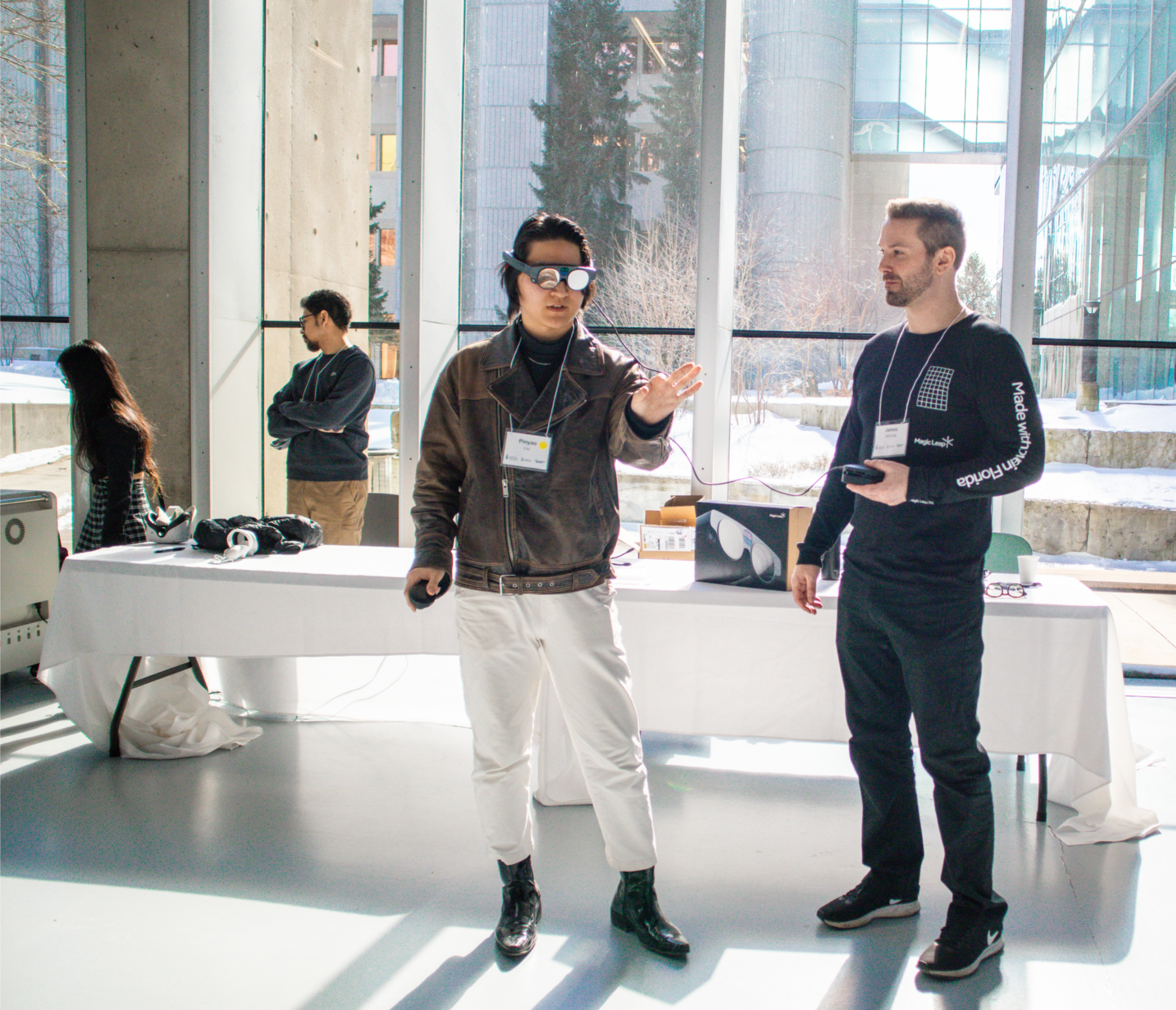 an attendee wearing an AR headset and beside him is James McCrae of Magic Leap showing him how to use it