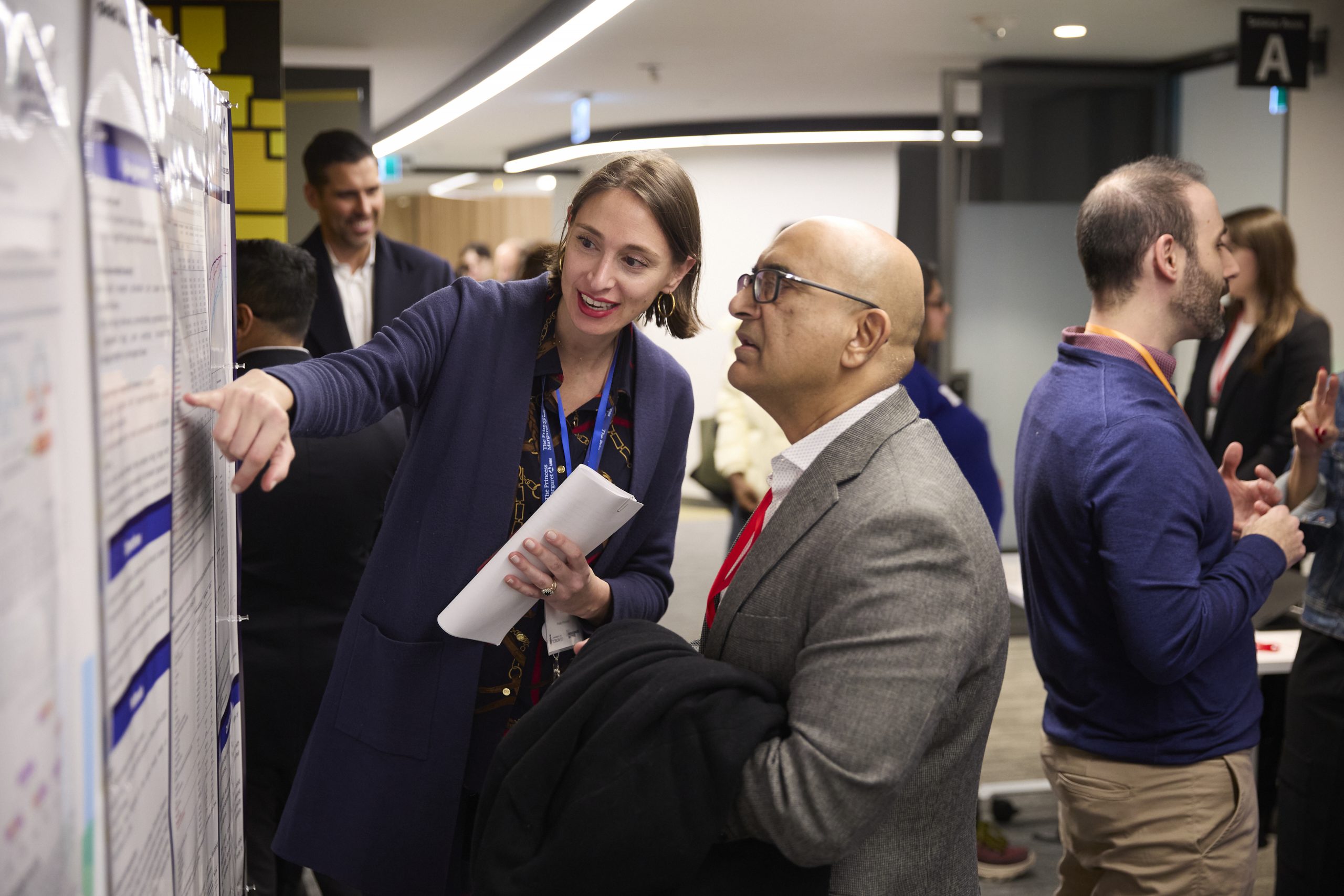 A presenter explains her poster in front of the AstraZeneca Canada booth